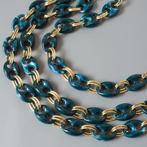 Detail of dark blue marble resin chain links with gold metal double ring connectors