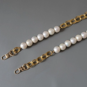 Detail of white iridescent pearl and gold metal chain with U-shaped spring hooks