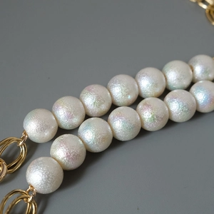 Macro shot of colorful cotton pearl beads and golden metal loop connectors for bag straps