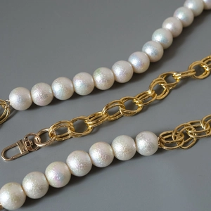 Detail of white iridescent pearl and gold metal chain strap with lobster clasp