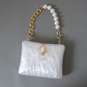 Detail of marble pattern acrylic handbag with gold metal and white pearl chain handle