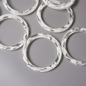 Detailed macro view of semi-transparent acrylic rings with white marble texture effect