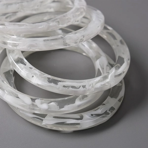 Stack of 11.5cm acrylic rings with white marble pattern on dark leather background