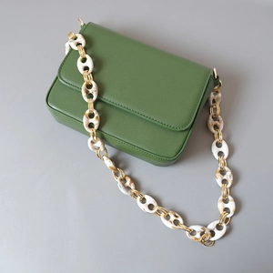 Detail of moss green matte leather bag with chunky marble texture acrylic chain strap