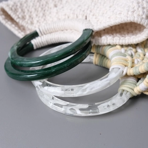 Detail of acrylic resin handles attached to handmade crochet bags in contrasting colors