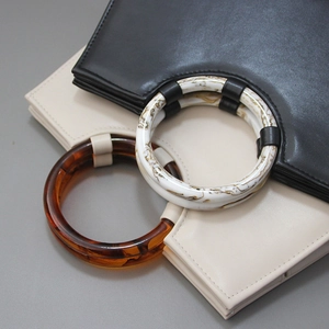 Detail of round resin handles with marble and tortoise shell patterns on leather bags