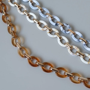 Detail of colorful resin acrylic chains with marble textures and gold metal buckles