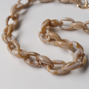 Macro view of vintage brown marble resin chain with a shiny gold metal ring buckle