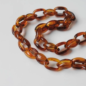Detailed close-up of amber acrylic resin chain strap with thick oval link design