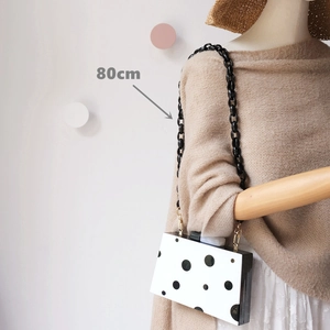Detail showing an 80cm black resin chain on a polka dot acrylic box clutch bag