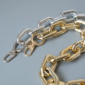 Close-up of thick gold and silver metal chain straps with lobster clasps for handbags