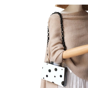 Vintage acrylic clutch bag with black polka dots and resin chain strap on mannequin