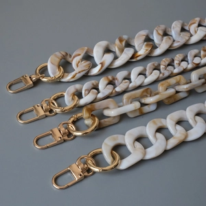 Detail of tortoiseshell acrylic resin bag straps with polished gold metal hardware