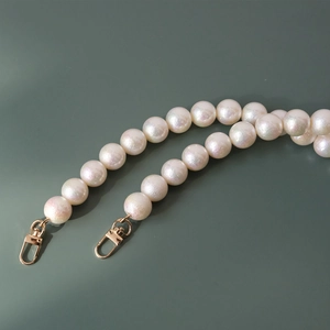 Detailed macro view of iridescent white cotton pearls on a stylish bag chain strap