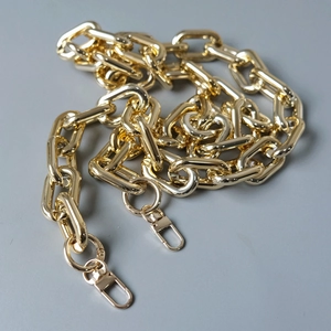 Close-up of a chunky golden metal chain strap with polished rectangular links and lobster clasps
