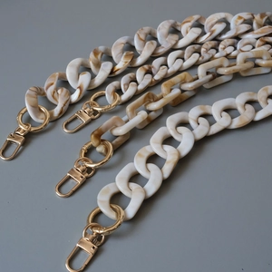 Detail view of acrylic resin bag chains with marble texture and gold lobster clasps