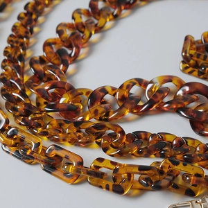 Macro detail of tortoiseshell acrylic chain links with gold lobster clasp for bags