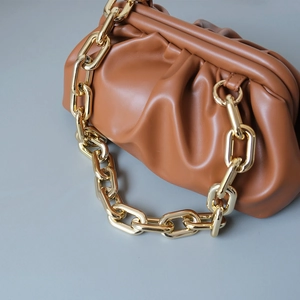 Detail view of caramel brown pleated dumpling bag with chunky gold metal chain strap