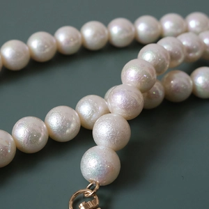 Macro view of iridescent mermaid pearl chain with detailed golden metallic clasp