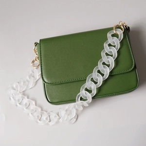 Green leather crossbody bag featuring a frosted white acrylic chain handle and gold hardware