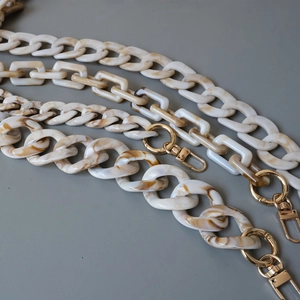 Detailed macro of beige acrylic resin bag chains with vintage marble texture and gold clasps