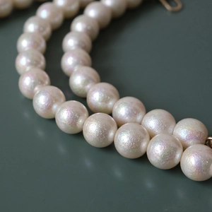 Macro shot of iridescent white pearl strap featuring glossy surface and metal clasp detail