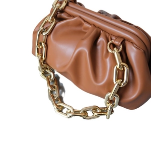 Brown leather cloud pouch bag with thick gold chain strap shown from side angle