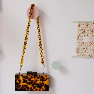 Detail of tortoiseshell acrylic handbag hanging with a thick chunky matching resin chain