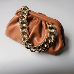 Caramel pleated cloud clutch bag with thick chunky gold chain strap on white background