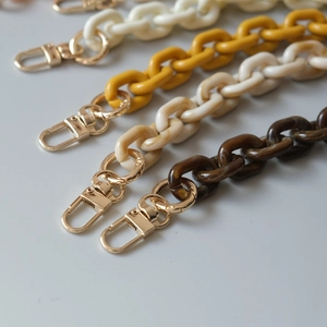 Detailed macro of acrylic resin bag chains in white, yellow and amber with gold metal clasps