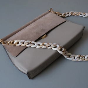 Detail of marble acrylic chain strap and contrast leather suede flap bag with gold buckle