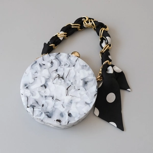 Detail of round marble texture handbag with gold chain and silk scarf wrap handle