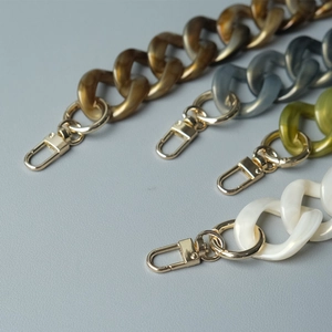Detalle de cadenas para bolsos en resina acrílica ámbar, gris, verde y blanco con cierres oro