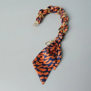 Detail of silk scarf intertwined with gold metal chain for handbag replacement strap