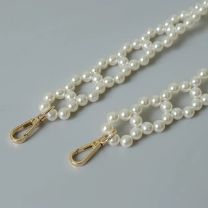 Detail of woven faux pearl bag strap with polished light gold metal lobster clasps