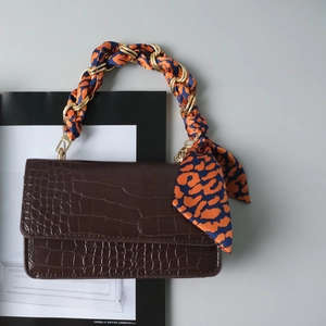 Brown crocodile leather handbag featuring a gold chain handle wrapped in a leopard silk scarf