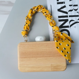Detail of wooden clutch featuring a silk-wrapped gold chain and marble ball clasp