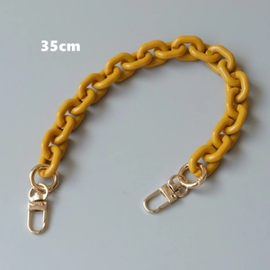 Macro detail of 35cm yellow acrylic chain strap with gold lobster clasps and metal rings