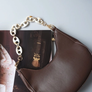 Detail of coffee half-moon bag featuring marble resin and gold metal chain strap