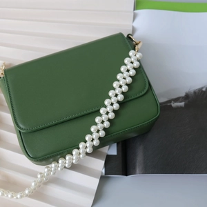 Détail d'un sac bandoulière en cuir vert foncé doté d'une chaîne décorative en perles