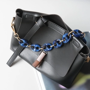 Close-up of black PU leather shoulder bag with blue marble texture resin chain link