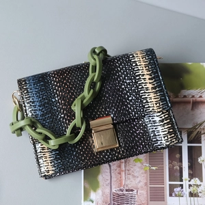 Detail of faux snake skin handbag with dark green acrylic chain and gold buckle