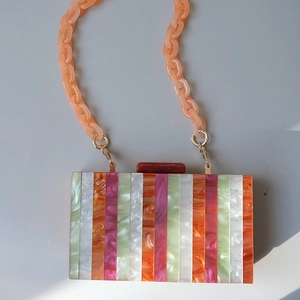 Detailed macro of colorful marble texture acrylic handbag with orange chain strap