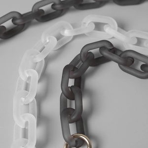 Macro shot of matte resin chain links in white and grey with gold ring attachment