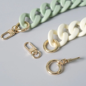 Detail of acrylic resin chain strap in green and cream with gold metal lobster clasps
