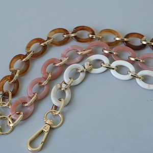 Gros plan de chaînes en résine acrylique ambre et marbre avec fermoirs mousquetons dorés