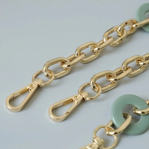 Detail of gold metal chain with green resin rings and swivel lobster clasps for bags
