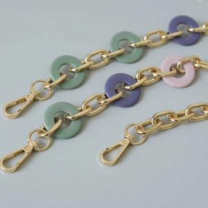 Close-up of colorful resin rings and gold metal chain straps with lobster clasps