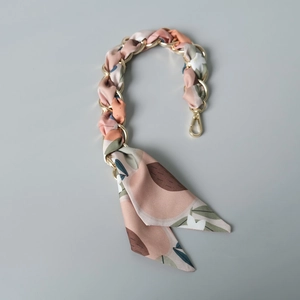 Détail de la poignée en chaîne dorée entrelacée d'un foulard en soie fleurie