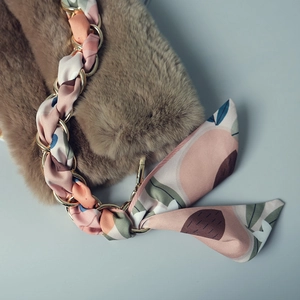 Détail de bandoulière en fausse fourrure avec chaîne dorée et ruban de soie floral rose
